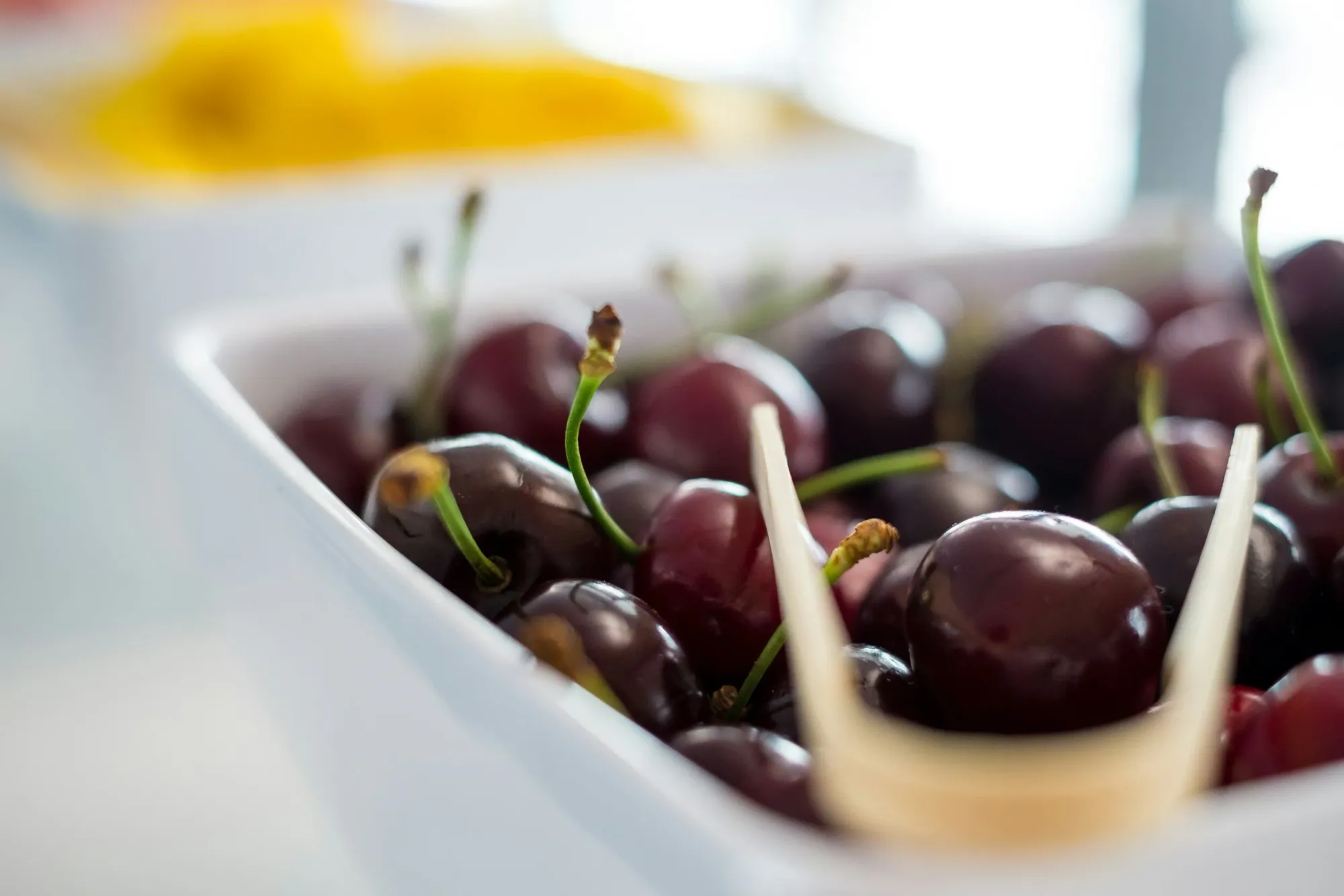 a bowl of cherries (in focus) next to a bowl of mango (out of focus)